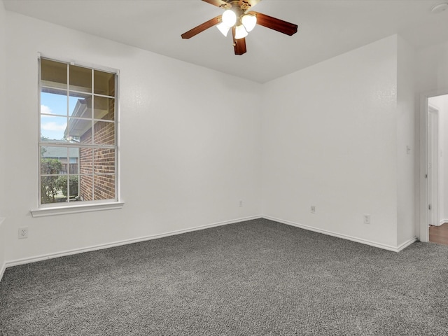 empty room featuring dark carpet, ceiling fan, and baseboards