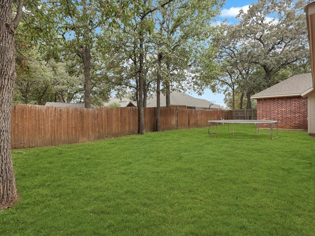 view of yard featuring a trampoline and a fenced backyard