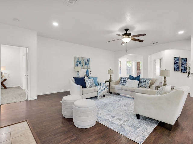 living area featuring visible vents, ceiling fan, arched walkways, and wood finished floors