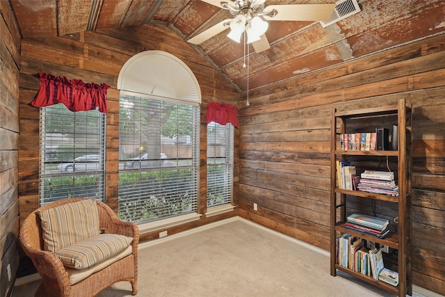 sitting room featuring wooden walls, ceiling fan, carpet, and lofted ceiling