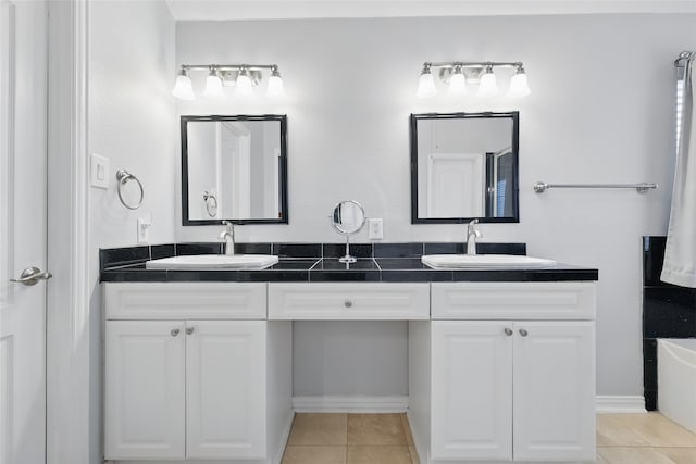 full bath featuring tile patterned flooring, double vanity, baseboards, and a sink