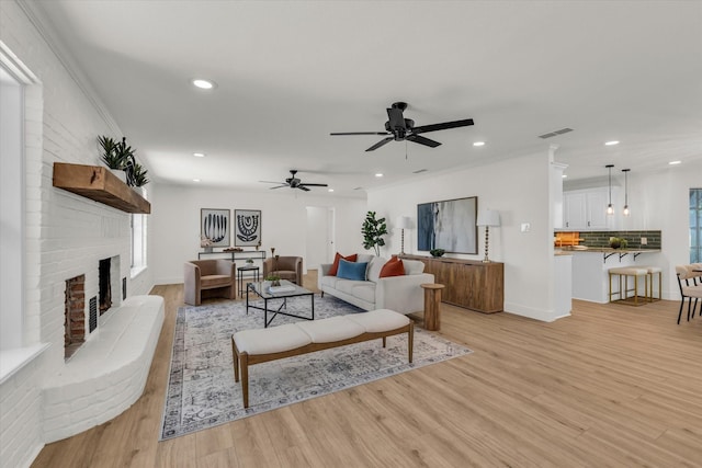 living area featuring recessed lighting, a brick fireplace, and light wood-type flooring