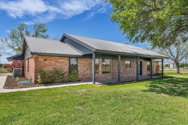 view of side of home with a yard, brick siding, metal roof, and central AC