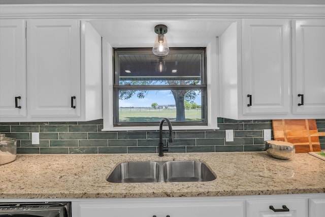 kitchen featuring white cabinets, a sink, and backsplash
