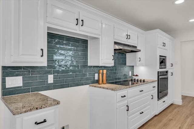 kitchen with white cabinets, under cabinet range hood, black electric stovetop, light stone countertops, and stainless steel oven