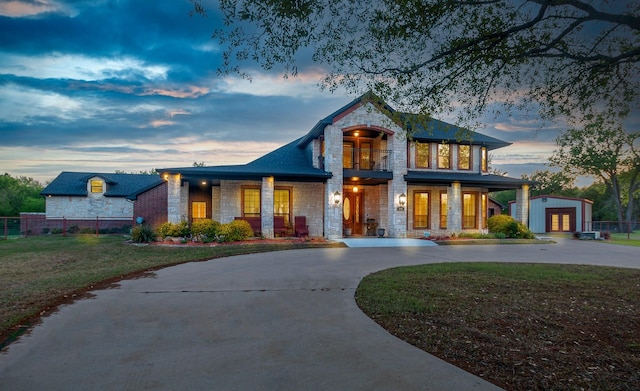 view of front of property with curved driveway, fence, stone siding, and a yard