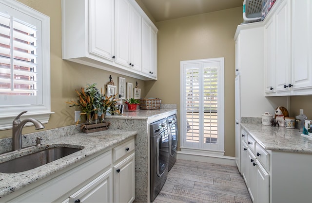 laundry room featuring a sink, washer and clothes dryer, cabinet space, and light wood-style flooring