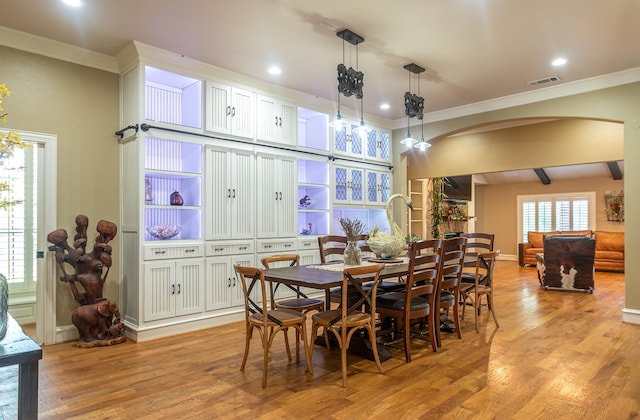 dining area featuring crown molding, visible vents, arched walkways, and light wood-style floors