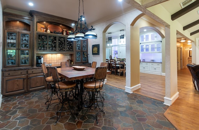 dining room featuring ornamental molding, recessed lighting, stone finish floor, visible vents, and arched walkways