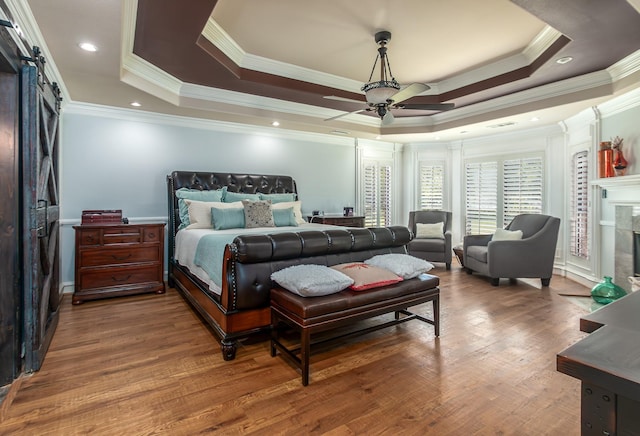 bedroom featuring a tiled fireplace, ornamental molding, and a tray ceiling