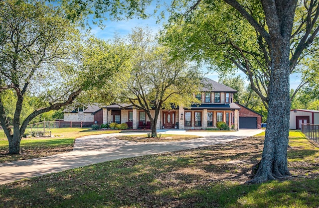 traditional-style home featuring a front yard, brick siding, driveway, and fence