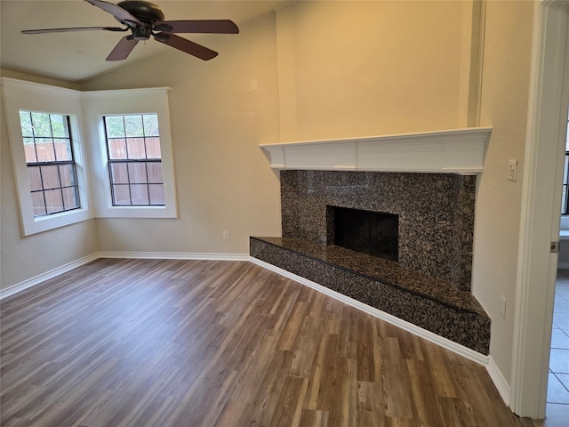 unfurnished living room featuring baseboards, a ceiling fan, lofted ceiling, a high end fireplace, and wood finished floors