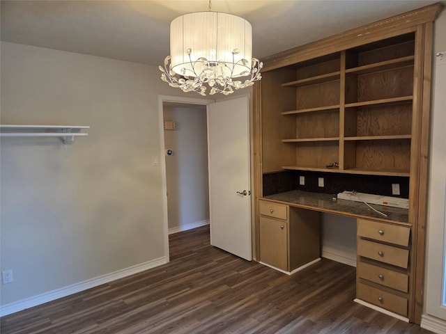 unfurnished office with built in desk, baseboards, a notable chandelier, and dark wood-style floors