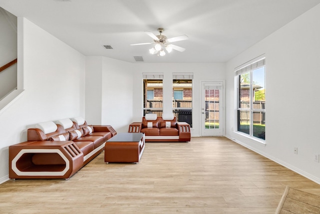 living room featuring visible vents, baseboards, a ceiling fan, and wood finished floors