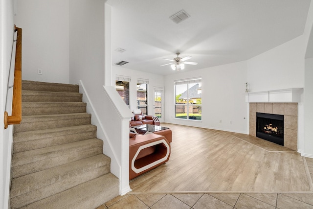 interior space with visible vents, ceiling fan, a tile fireplace, and wood finished floors