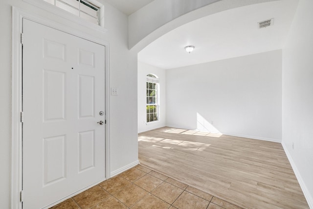 entrance foyer with visible vents, baseboards, arched walkways, and light tile patterned floors
