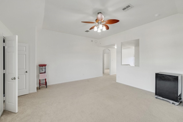 unfurnished living room featuring light carpet, ceiling fan, visible vents, and arched walkways