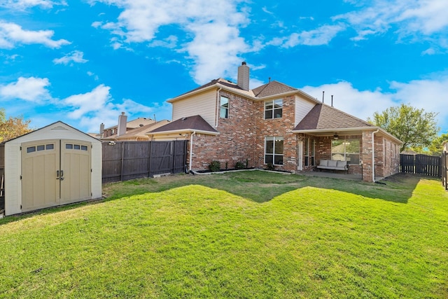 rear view of property with an outbuilding, a storage unit, a fenced backyard, and a yard