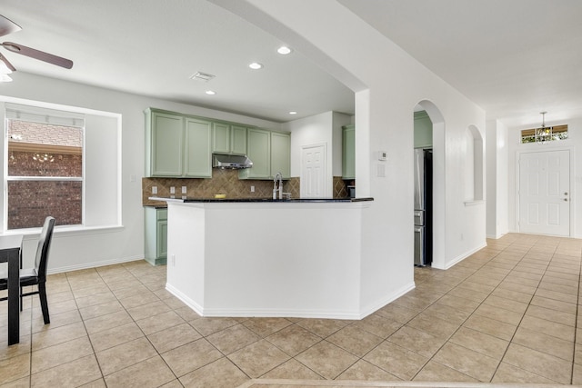 kitchen with freestanding refrigerator, a ceiling fan, under cabinet range hood, visible vents, and green cabinetry