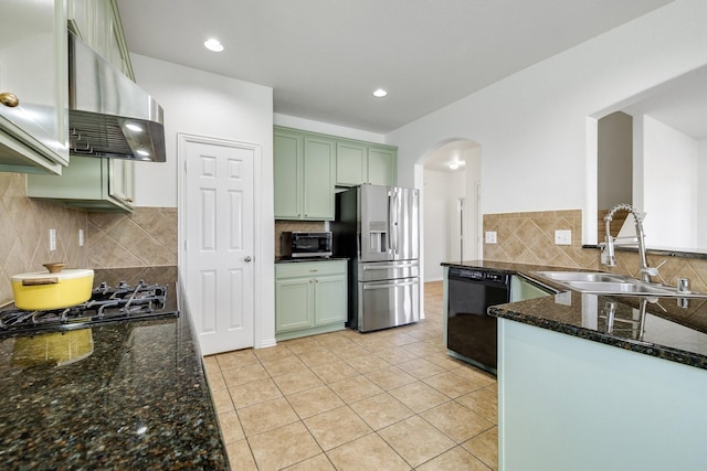 kitchen featuring arched walkways, a sink, black appliances, green cabinets, and extractor fan