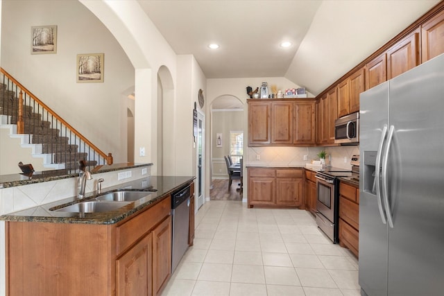 191 Cardiff Ln, Waxahachie, TX 75167 - kitchen featuring light tile patterned flooring, a sink, dark stone countertops, arched walkways, and stainless steel appliances