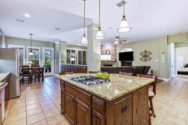 kitchen featuring appliances with stainless steel finishes, ceiling fan, light tile patterned floors, and a fireplace