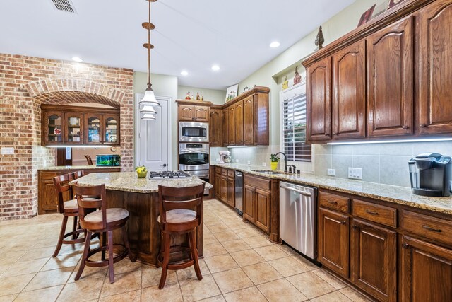 kitchen featuring appliances with stainless steel finishes, a sink, a center island, backsplash, and a breakfast bar