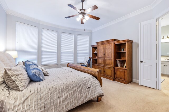 bedroom with crown molding, light colored carpet, ensuite bath, baseboards, and ceiling fan