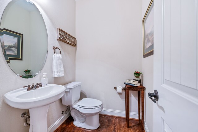half bath featuring wood finished floors, baseboards, and toilet