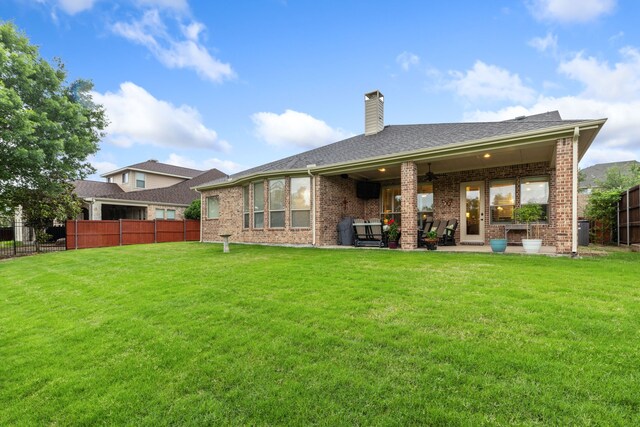 rear view of house with ceiling fan, a chimney, brick siding, and a patio