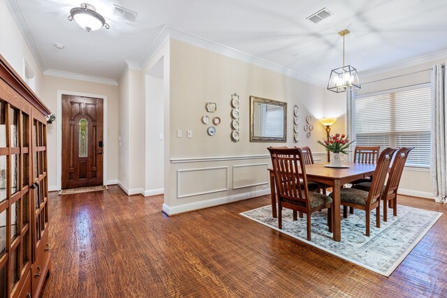 dining room featuring healthy amount of natural light, a chandelier, dark wood-type flooring, crown molding, and baseboards