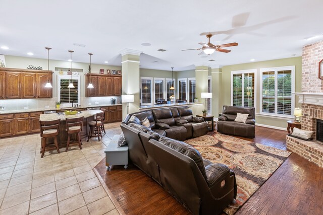living room with ceiling fan, a fireplace, recessed lighting, ornate columns, and light tile patterned flooring