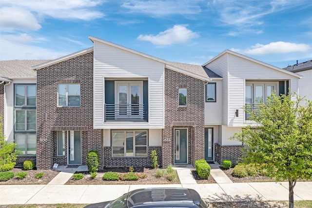 townhome / multi-family property with brick siding and a balcony