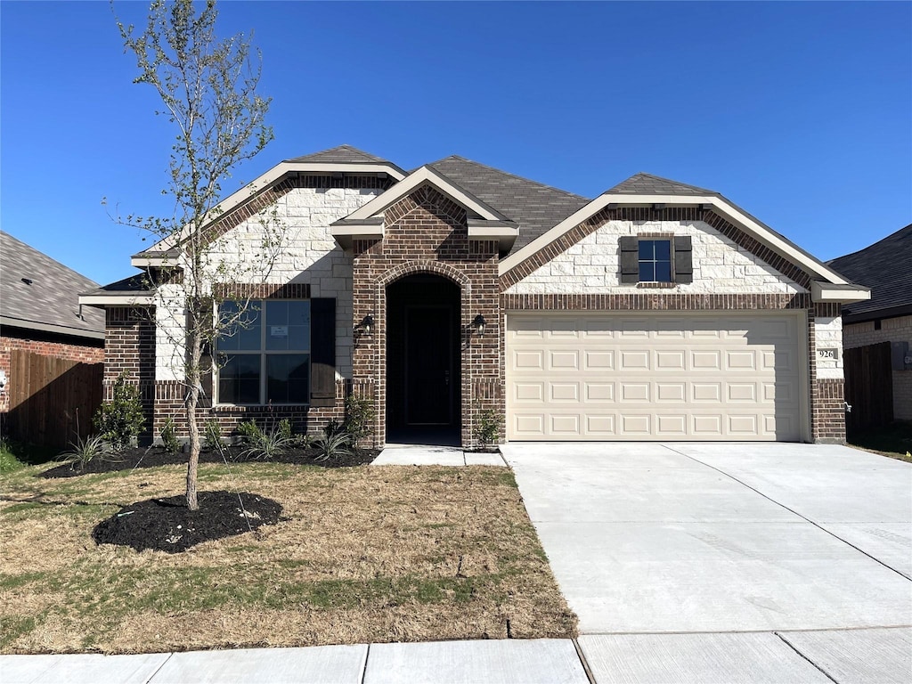 french country inspired facade featuring concrete driveway, a garage, and brick siding