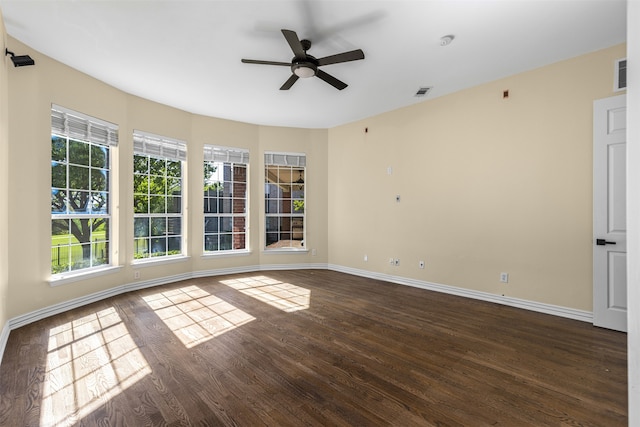 empty room with visible vents, baseboards, a ceiling fan, and dark wood-style floors