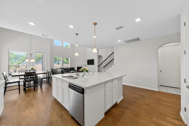 kitchen with a sink, visible vents, stainless steel dishwasher, and a warm lit fireplace