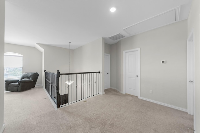hallway featuring visible vents, baseboards, attic access, and carpet