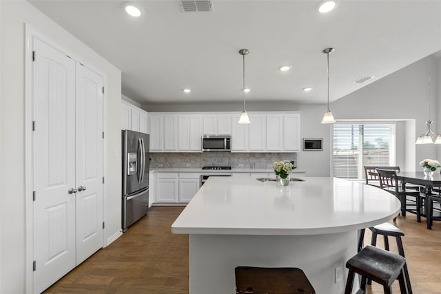 kitchen with a breakfast bar area, backsplash, visible vents, and stainless steel appliances
