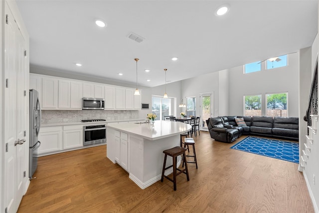 kitchen with stainless steel appliances, light wood finished floors, visible vents, and white cabinetry