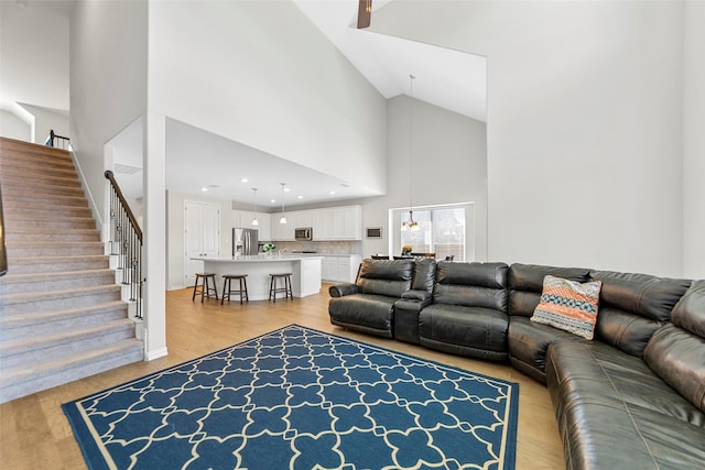 living area featuring high vaulted ceiling, recessed lighting, stairway, and light wood finished floors