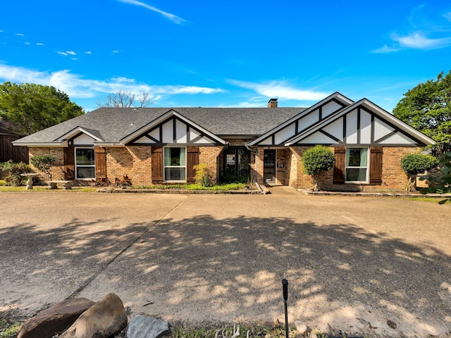 1770 Plummer Dr, Rockwall, TX 75087 - tudor home featuring brick siding, a chimney, and a shingled roof