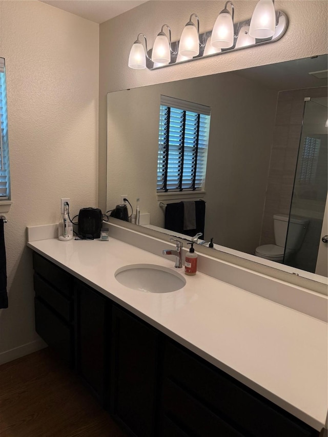 2365 Norwood Dr, Dallas, TX 75228 - full bathroom featuring toilet, wood finished floors, vanity, a textured wall, and a shower