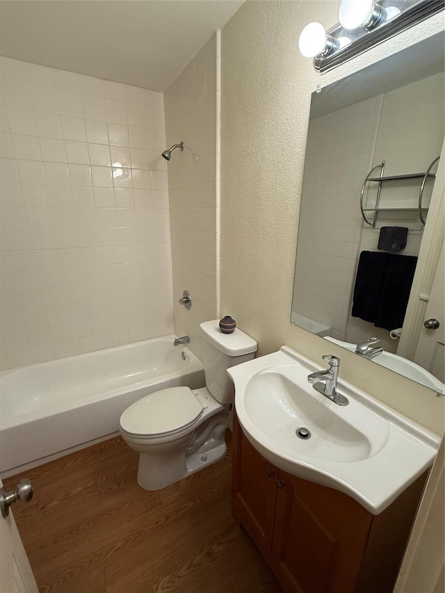 2365 Norwood Dr, Dallas, TX 75228 - full bathroom with wood finished floors, a textured wall, toilet, vanity, and shower / washtub combination