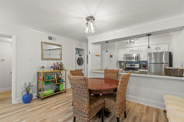 5925 E University Blvd Unit 133, Dallas, TX 75206 - dining room featuring baseboards, stacked washer and dryer, ornamental molding, light wood-style floors, and visible vents