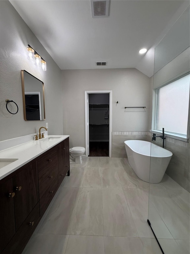2610 Eganridge Ln, Rockwall, TX 75087 - bathroom featuring double vanity, a soaking tub, toilet, a walk in closet, and vaulted ceiling
