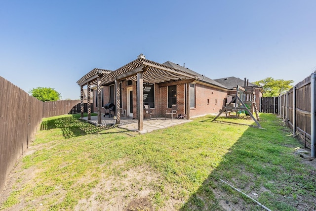 back of house with a fenced backyard, a lawn, a patio, a playground, and brick siding