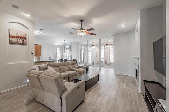 living area featuring a fireplace, light wood-type flooring, a ceiling fan, recessed lighting, and baseboards