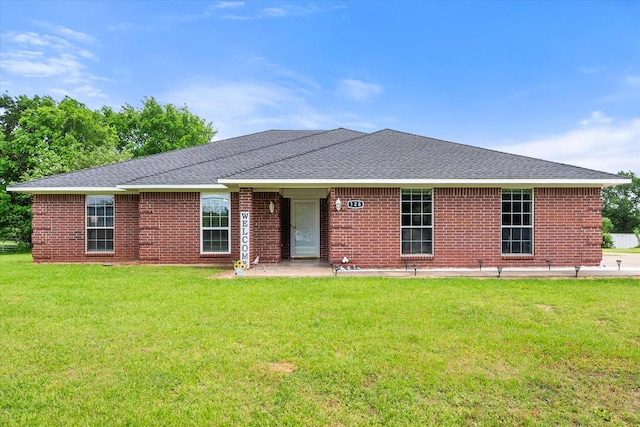 rear view of property with brick siding, a patio area, a lawn, and a shingled roof