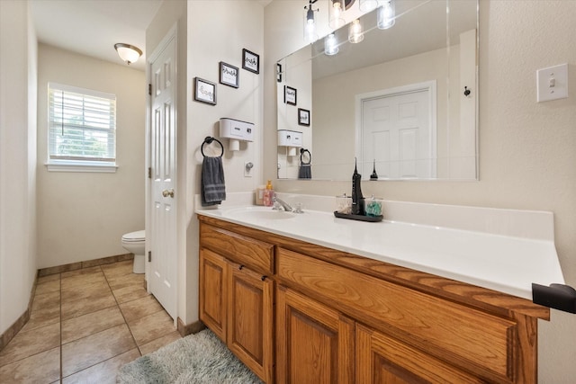 bathroom with toilet, vanity, tile patterned floors, and baseboards