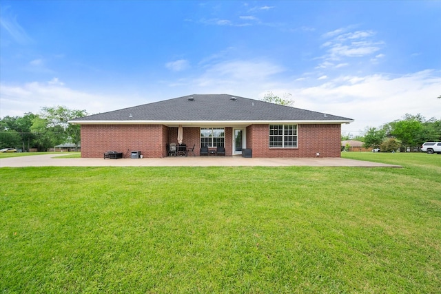 back of property with a yard, brick siding, and a patio area